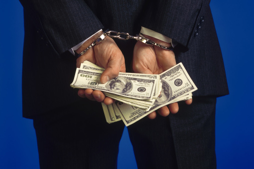 man handcuffs holding hundred dollar bills