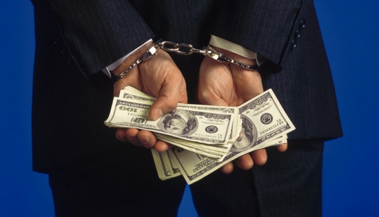 a businessman handcuffed holding cash